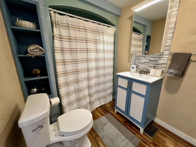 bathroom featuring toilet, hardwood / wood-style flooring, a textured ceiling, built in features, and vanity