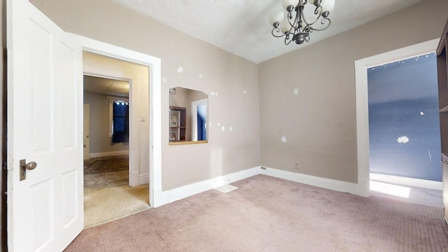 carpeted empty room with an inviting chandelier and a textured ceiling