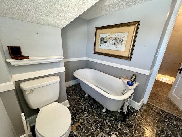 bathroom featuring toilet, a textured ceiling, and a bath