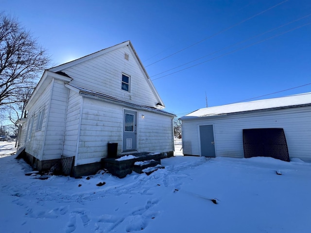 snow covered rear of property with a garage