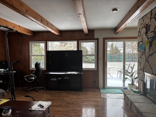 living room with a wealth of natural light, beam ceiling, dark hardwood / wood-style flooring, and wooden walls