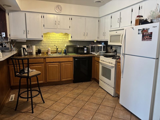 kitchen featuring light tile patterned floors, white cabinetry, decorative backsplash, black appliances, and sink