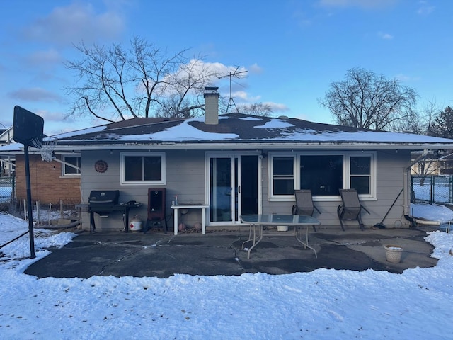 snow covered back of property with a patio