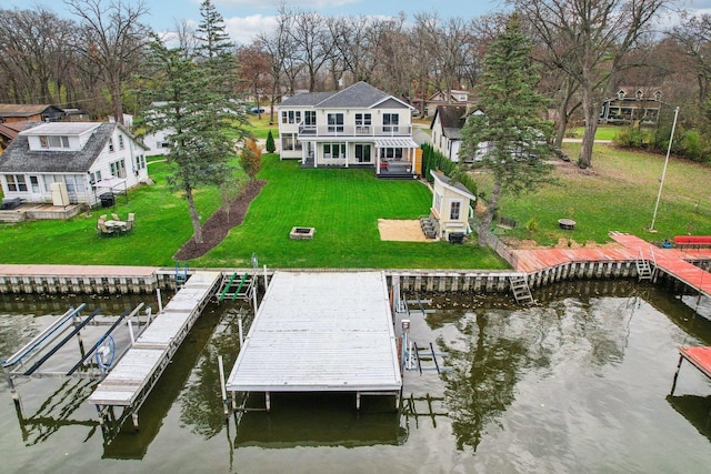 dock area featuring a fire pit, a water view, and a lawn