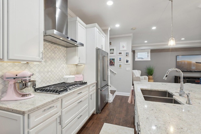 kitchen featuring white cabinetry, wall chimney range hood, sink, and hanging light fixtures