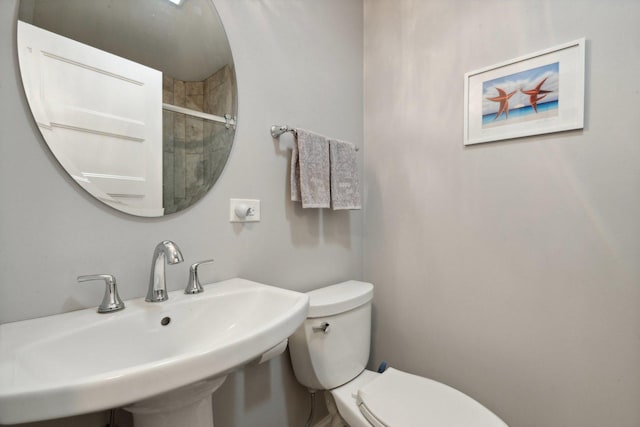 bathroom featuring toilet, a shower with door, and sink