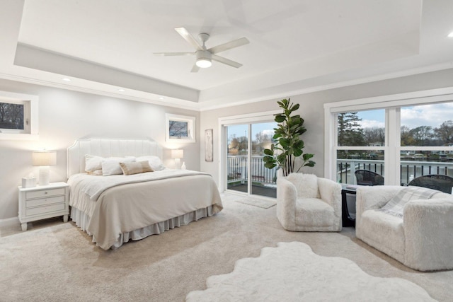 carpeted bedroom featuring access to exterior, multiple windows, a tray ceiling, and ceiling fan