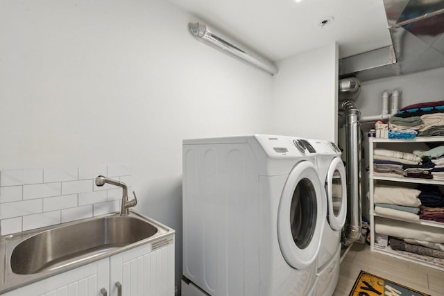 clothes washing area featuring washer and clothes dryer, sink, cabinets, and light hardwood / wood-style flooring