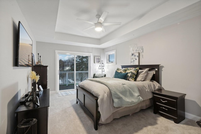 bedroom featuring a tray ceiling, access to exterior, ceiling fan, and light colored carpet