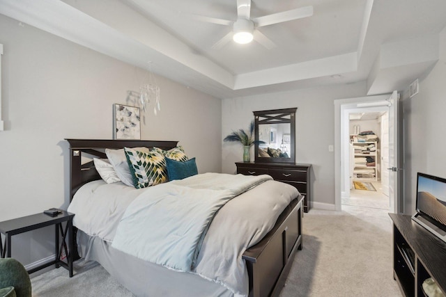 carpeted bedroom featuring a tray ceiling and ceiling fan