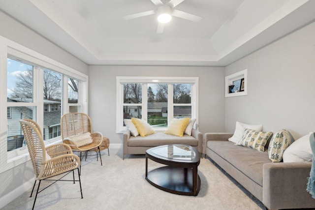 carpeted living room featuring a raised ceiling and ceiling fan