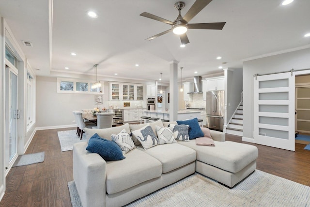 living room with crown molding, wine cooler, ceiling fan, a barn door, and wood-type flooring