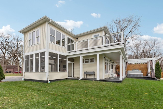 rear view of property with a lawn, a sunroom, and a balcony