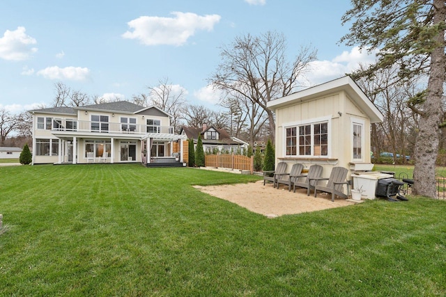 rear view of property with a balcony and a yard