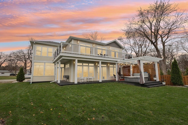 back house at dusk featuring a balcony, a pergola, and a yard