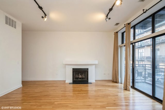 unfurnished living room with light hardwood / wood-style flooring and rail lighting