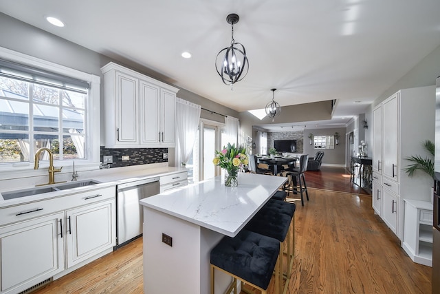 kitchen featuring white cabinets, a center island, stainless steel dishwasher, and sink