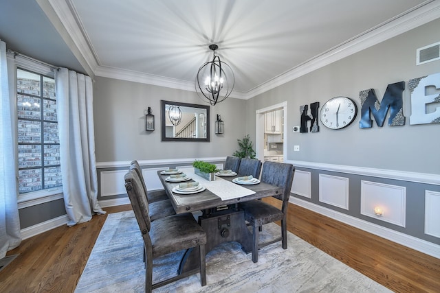 dining room with hardwood / wood-style flooring, a notable chandelier, and ornamental molding