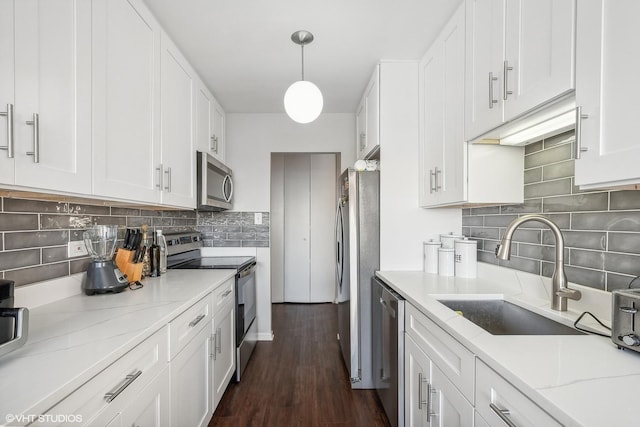 kitchen featuring light stone countertops, white cabinetry, sink, hanging light fixtures, and appliances with stainless steel finishes