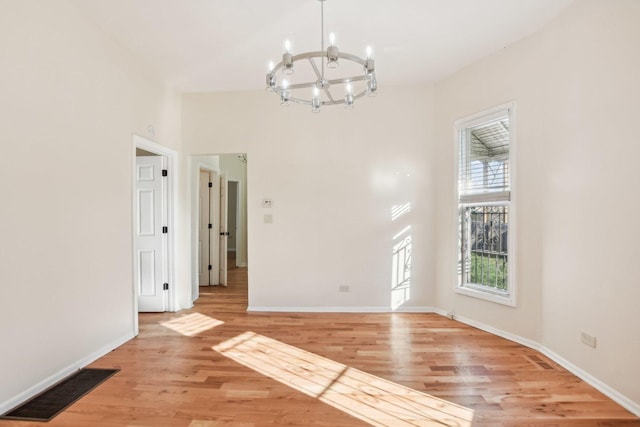 unfurnished dining area with light hardwood / wood-style floors and a notable chandelier