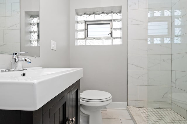 bathroom featuring toilet, vanity, tile patterned floors, and tiled shower