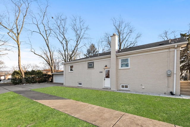 back of property with a garage, an outbuilding, and a lawn