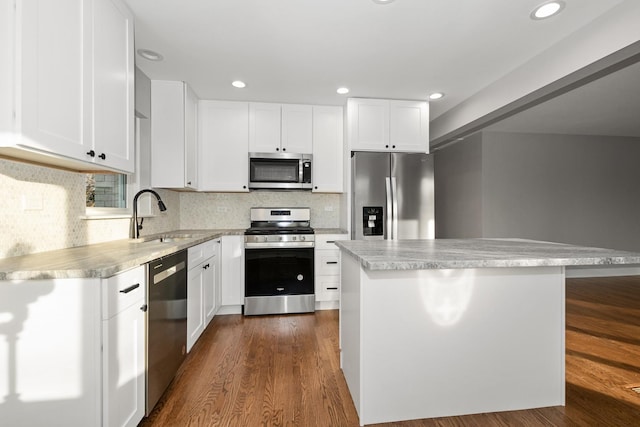 kitchen with appliances with stainless steel finishes, decorative backsplash, a kitchen island, white cabinets, and sink