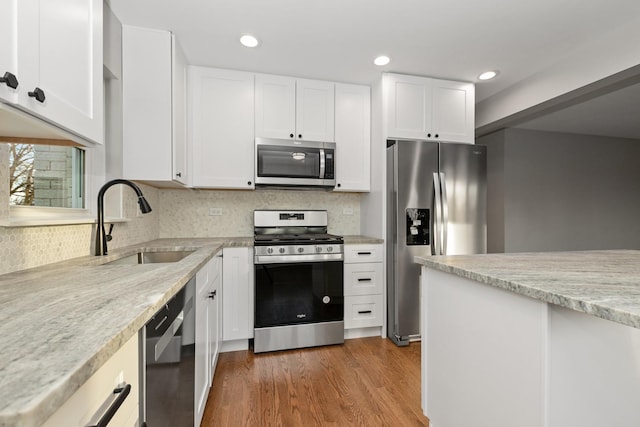 kitchen featuring light stone countertops, appliances with stainless steel finishes, white cabinetry, dark hardwood / wood-style flooring, and sink