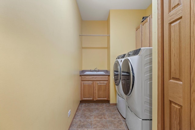 laundry area featuring washer and clothes dryer, a sink, and cabinet space