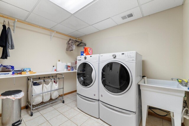 laundry room with laundry area, washing machine and clothes dryer, visible vents, light tile patterned floors, and a sink