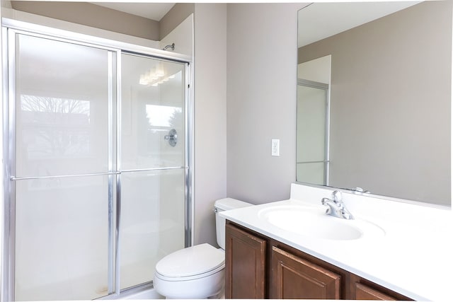 bathroom featuring vanity, toilet, and a shower with shower door