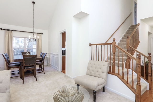 dining area featuring light carpet, high vaulted ceiling, and an inviting chandelier