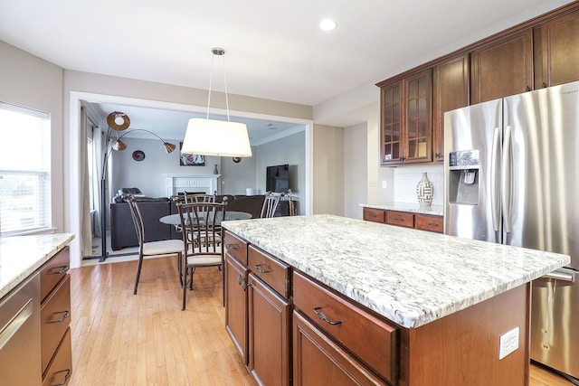 kitchen with tasteful backsplash, light hardwood / wood-style flooring, stainless steel refrigerator with ice dispenser, pendant lighting, and a kitchen island