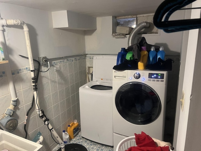 washroom featuring tile walls, washing machine and dryer, and sink