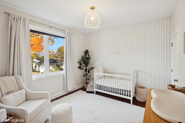 bedroom featuring a nursery area and wood-type flooring