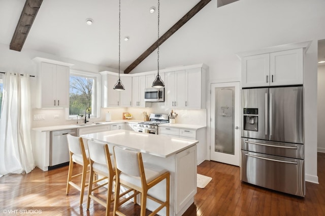 kitchen with white cabinets, sink, a kitchen island, beam ceiling, and stainless steel appliances