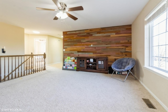 unfurnished room featuring carpet floors, ceiling fan, and wooden walls