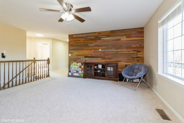 unfurnished room featuring carpet flooring, ceiling fan, and wood walls