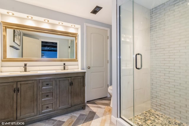 bathroom with vanity, toilet, and a shower with shower door