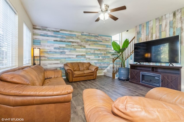 living room featuring ceiling fan, a fireplace, and dark wood-type flooring