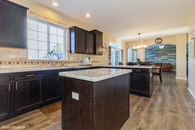 kitchen with kitchen peninsula, sink, a kitchen island, and decorative light fixtures