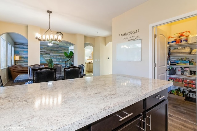 kitchen with light stone counters, dark hardwood / wood-style flooring, decorative light fixtures, and an inviting chandelier