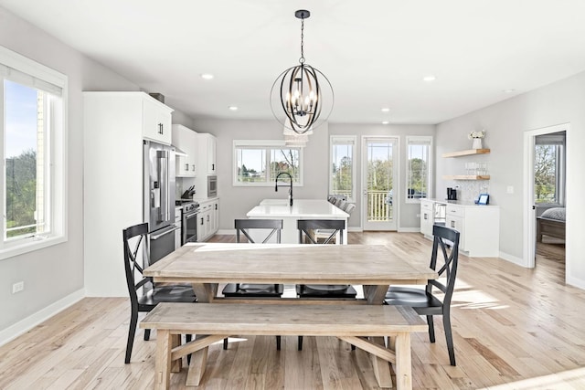 dining area featuring plenty of natural light, sink, light hardwood / wood-style flooring, and an inviting chandelier