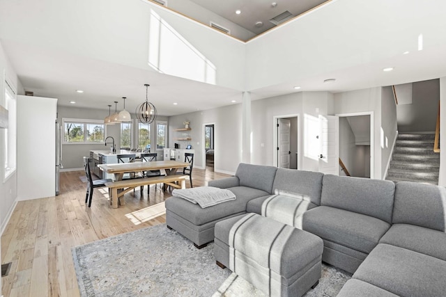 living room with light wood-type flooring, sink, and a high ceiling