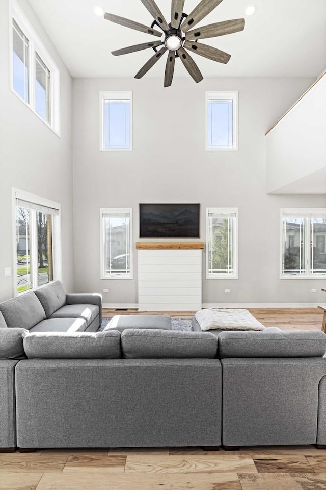 living room with hardwood / wood-style flooring, ceiling fan, and a towering ceiling