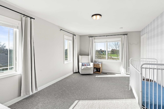 unfurnished bedroom with carpet flooring, a crib, and multiple windows