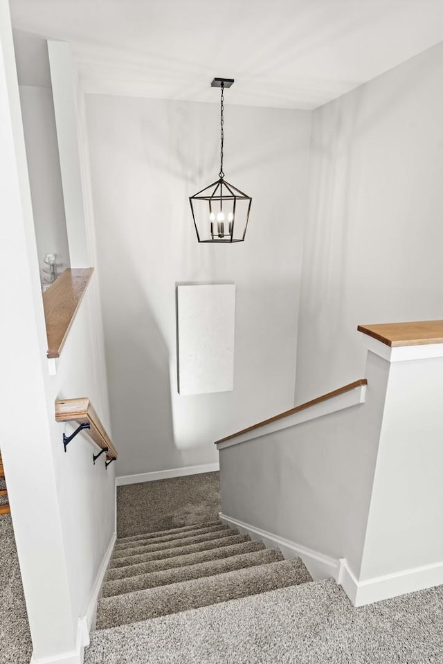 staircase with a chandelier and carpet floors