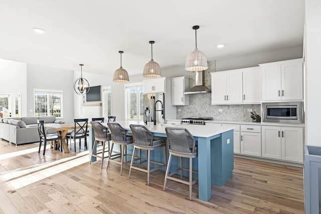 kitchen with white cabinets, wall chimney range hood, and stainless steel appliances