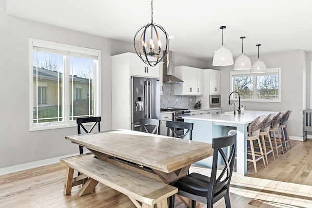 dining room with a healthy amount of sunlight, a notable chandelier, and light wood-type flooring