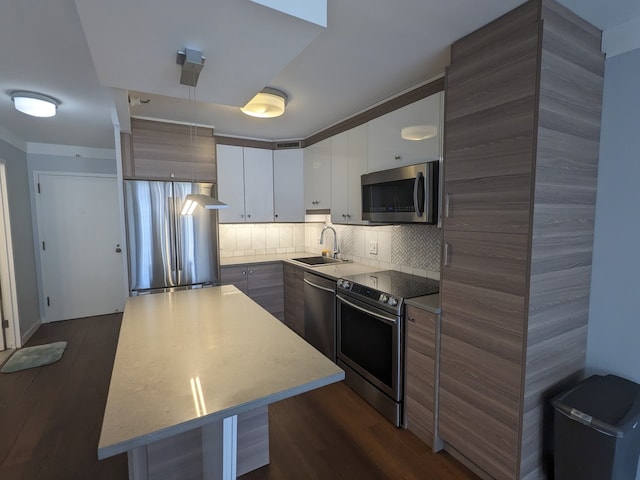 kitchen with a center island, backsplash, white cabinets, sink, and stainless steel appliances